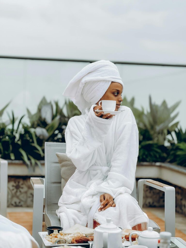 Woman in bathrobe enjoying coffee outdoors at a hotel in the morning.